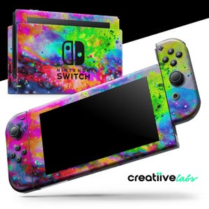 Puede incluir: Una consola Nintendo Switch y sus mandos con un diseño abstracto y colorido. El diseño presenta una mezcla de tonos rosas, azules, verdes y amarillos, creando una apariencia vibrante similar a una galaxia. El logotipo de Nintendo Switch es visible.