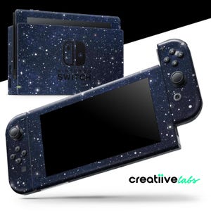 May include: A Nintendo Switch console and controllers with a dark blue galaxy-themed skin. The skin features white speckles resembling stars. The console and controllers are displayed on a white background. The Nintendo Switch logo is visible.
