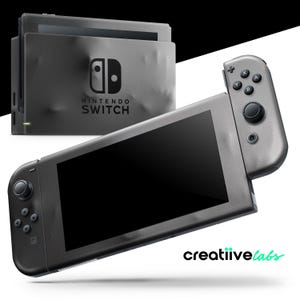 Op de afbeelding: Een grijze Nintendo Switch-console met een zwart scherm en aangesloten controller. De console staat naast een grijs dockingstation met het Nintendo Switch-logo. De afbeelding heeft een witte en zwarte achtergrond.