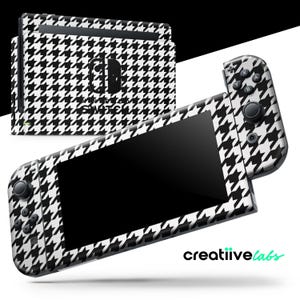 Op de afbeelding: Een zwart-wit hondenpootpatroon skin set voor een Nintendo Switch console. De set bevat skins voor de console en de Joy-Con controllers. De tekst "SWITCH" is zichtbaar op de console.