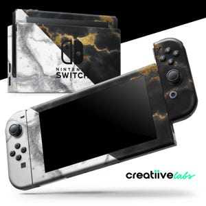 May include: A Nintendo Switch console and controllers with a marble design. The design features white, black, and gold accents. The console has the words "NINTENDO SWITCH" printed on it. The controllers have black buttons and joysticks.
