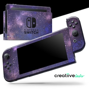 Puede incluir: Una consola Nintendo Switch y sus mandos con una funda con temática de galaxia. La funda presenta un diseño de nebulosa púrpura y rosa. La consola tiene el logotipo de Nintendo Switch en la parte delantera. Los mandos tienen botones negros.