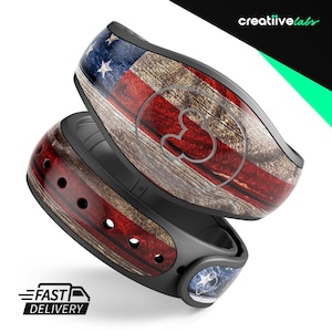 May include: A red, white, and blue American flag design with a wood grain texture on a black MagicBand. The MagicBand has a Mickey Mouse icon on the front.