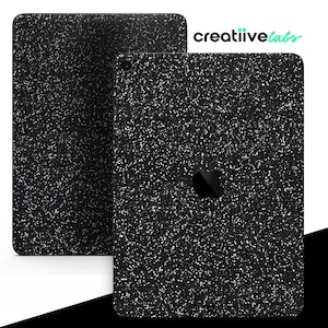 Op de afbeelding: Twee zwarte iPad-skins met een gespikkeld, glitterachtig ontwerp. Eén skin wordt plat weergegeven en de andere is schuin, waardoor het Apple-logo zichtbaar is. De tekst "creatiivelabs" staat in de rechterbovenhoek.