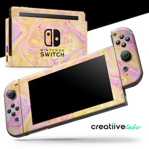 May include: A Nintendo Switch console and controllers with a colorful, marbled design in shades of pink, yellow, and white. The console features the Nintendo Switch logo. The controllers are attached to the screen, and the brand name "creatiivelabs" is visible.