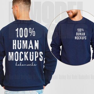 May include: A navy blue sweatshirt with long sleeves and a crew neck. The sweatshirt has the text "100% HUMAN MOCKUPS" printed on the front in white with a distressed font. The text "kokomocks" is printed below the main text in a smaller font.