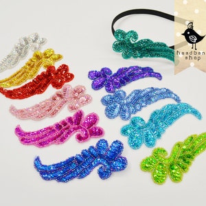 May include: Assortment of ten colorful sequined fabric patches in the shape of a stylized wing. The patches are in various colors including silver, gold, red, pink, purple, blue, turquoise, and green. The patches are arranged in a row on a white surface.