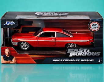 May include: A red die-cast model of Dom's Chevrolet Impala from the Fast & Furious movie franchise, displayed in its original packaging. The car has chrome wheels and is in a clear display box.