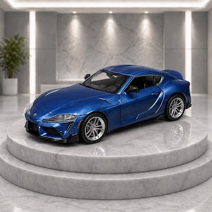 May include: A blue die-cast model sports car with silver wheels is displayed on a marble pedestal. The car has a sleek design with detailed features, including headlights and a rear spoiler. The car is a Toyota Supra.