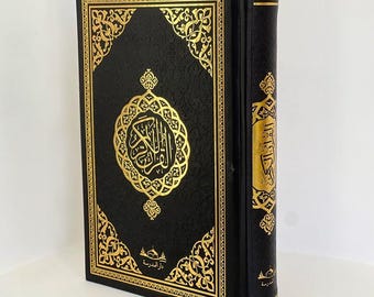 May include: A black leather-bound Quran with gold-coloured Arabic script and intricate designs. The cover features a circular design with the word "Allah" in Arabic script.