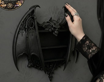 May include: A black bat-wing shaped shelf with two shelves and a skull design. The shelf is mounted on a grey wall. A circular sticker with the text "DIGITAL FILE FOR 3D PRINTING" is in the upper left corner.