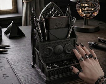 May include: A black gothic-style desk organizer with pen holders, a wallet, and a small drawer. The organizer features crescent moon and pentagram designs. The image also includes a hand with rings and a bracelet, and a digital file advertisement.