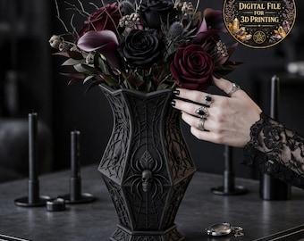 May include: A black vase with a spiderweb and skull design, holding a bouquet of dark red and black flowers. The vase is on a dark surface, with a hand wearing rings and a pocket watch visible.