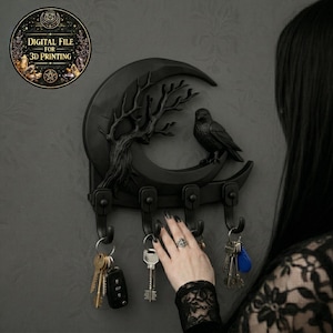 May include: A black key holder in the shape of a crescent moon, featuring a tree and raven design. The key holder has three hooks and is mounted on a grey wall. The image includes a circular graphic that says "DIGITAL FILE FOR 3D PRINTING".