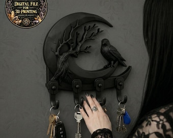 May include: A black key holder shaped like a crescent moon with a tree and raven design. The key holder has three hooks and is mounted on a gray wall. The image includes a circular graphic that says "DIGITAL FILE FOR 3D PRINTING".