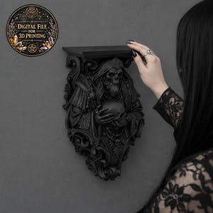 May include: A black wall shelf featuring a detailed, gothic-style sculpture of a robed skeleton holding a sphere. The shelf has a flat top and ornate carvings. A circular graphic with text "DIGITAL FILE FOR 3D PRINTING" is visible.