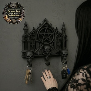 May include: Black gothic key holder featuring a pentagram, skull, and bat wing design. The key holder has three hooks for keys and the text "DIGITAL FILE FOR 3D PRINTING" in a circular emblem.