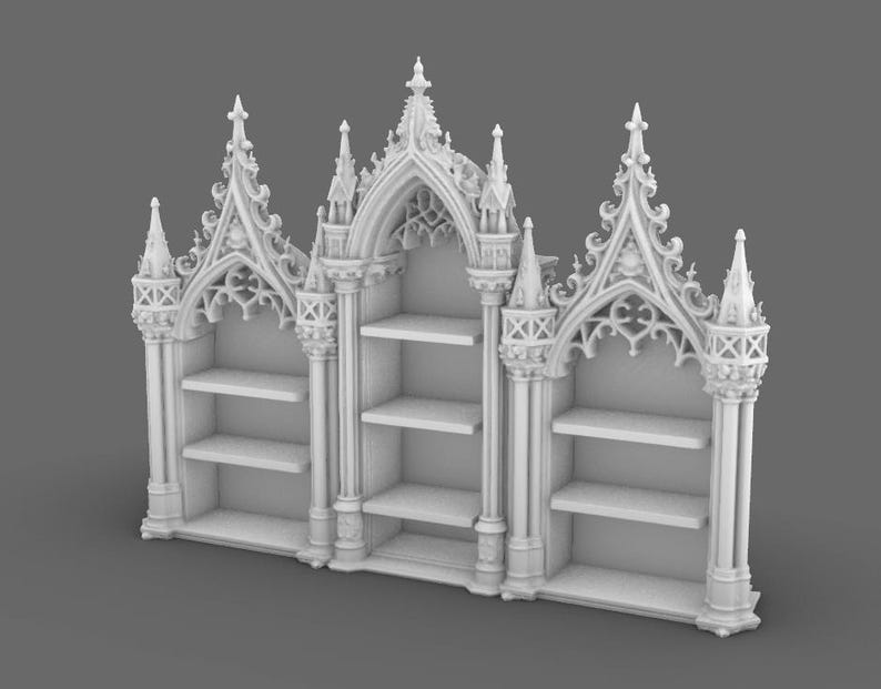 May include: A white, ornate bookshelf with a gothic architectural design. The bookshelf features three sections with shelves, topped with pointed arches and decorative spires. The overall design is symmetrical and detailed.