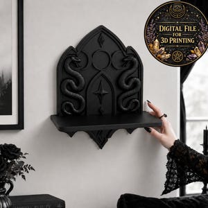 May include: A black wall-mounted shelf featuring a gothic arch design with two sculpted snakes, a central star, and a triple moon symbol. The upper portion has a decorative back panel, and a circular badge reads Digital File for 3D Printing.