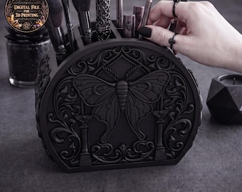 May include: Black makeup brush holder with a detailed moth and floral design. The holder contains makeup brushes, lipsticks, and pencils. The holder is made of a dark material and has a digital file for 3D printing logo.