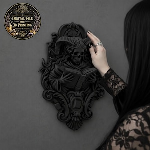 Op de afbeelding: Zwarte gotische wanddecoratie met een gehoornde schedel die een boek leest. Het ontwerp is sierlijk en gedetailleerd, met een donkere, matte afwerking. De tekst "DIGITAL FILE FOR 3D PRINTING" is zichtbaar op een cirkelvormige afbeelding.