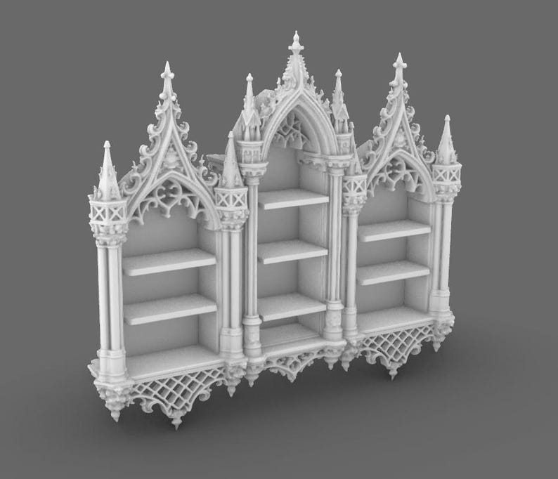 May include: A white, Gothic-style bookshelf with three sections. Each section has shelves for storage. The bookshelf features ornate architectural details, including pointed arches, spires, and decorative tracery. The overall design is reminiscent of a cathedral or church.