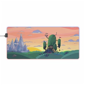 May include: Rectangular mouse pad featuring a cartoon landscape with a sunset sky, green hills, and a large treehouse. The pad has a black power cord and a glowing red and purple border.