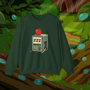 May include: Dark green sweatshirt with a cartoon graphic of a retro video game console, displaying "ZZZ" on the screen and a red apple. The console has "BMC" on the side. The sweatshirt is a casual garment.