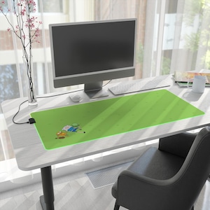 May include: A green rectangular desk mat featuring a cartoon illustration of two characters. The mat is on a white desk with a computer, keyboard, and mouse. A black chair is in front of the desk.