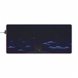 May include: Rectangular gaming mouse pad with a pixelated night sky design, featuring a small house on a hill, clouds, and stars. The pad has a black border and a red and blue LED light strip.