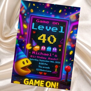 Könnte beinhalten: Eine farbenfrohe Einladung im Retro-Videospiel-Design. Das Design zeigt den Text "Game on Level 40" mit pixeligen Zahlen und Zeichen. Enthält die Details für Michaels Geburtstagsparty, mit Pac-Man und einem Joystick.