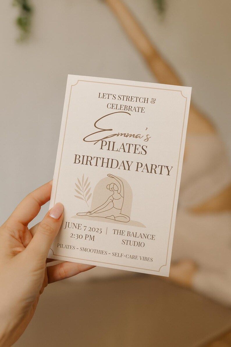 Close-up of a hand holding a minimalist Pilates birthday invitation in a serene yoga studio setting. The beige and brown tones match the calm, self-care vibe, with a blurred background showing a woman stretching on a mat. Perfect for Etsy listings promoting wellness or Pilates-themed parties