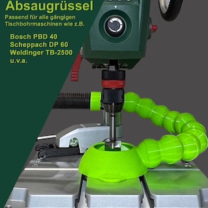 Könnte beinhalten: Grüne Bohrmaschine mit einem grünen Staubabsaugschlauch, der am Bohrer befestigt ist. Die Bohrmaschine ist auf einem silbernen Tisch mit einem grünen Staubauffangbehälter montiert.