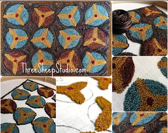May include: A close-up of a needlepoint project in progress. The design features a repeating pattern of three-pointed stars in shades of brown, blue, and gold. The project is being worked on a white canvas and is framed in a wooden hoop. The text "ThreeSheepStudio.com" is visible in the image.