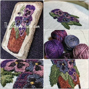 May include: A close-up of a needlepoint project featuring a potted arrangement of purple pansies. The project is framed in a white rectangle and is surrounded by a dark purple background. The image also shows the yarn used for the project, which is a variety of shades of purple.