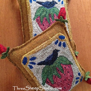 May include: Two needlepoint pillows with a brown background and a white center. Each pillow features a black bird perched on a green leaf with a red and green strawberry. The pillows have a gold trim and blue accents. The text "Three Sheep Studio.com" is visible at the bottom of the image.