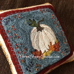 May include: A handmade, blue and white pumpkin pillow with fall leaves and berries embroidered on a red background. The pillow has a gold beaded trim and the text "ThreeSheepStudio.com" is embroidered on the bottom.