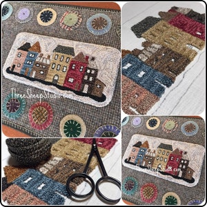 May include: A close-up of a rug hooking project depicting a row of houses with a brown, gray, and white color scheme. The houses are surrounded by a border of colorful circles. The text "ThreeSheepStudio.com" is visible in the bottom left corner of the image.