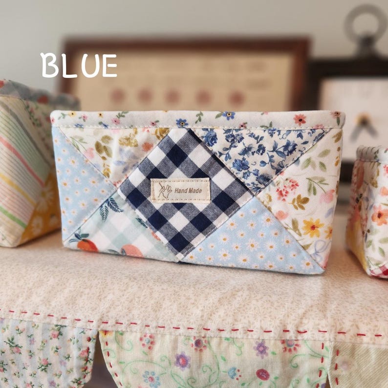 Pode incluir: Uma cesta de tecido feita &agrave; m&atilde;o com um design de patchwork. A cesta apresenta uma mistura de padr&otilde;es florais, xadrez e bolinhas em cores azul, branco e pastel. O texto "BLUE" est&aacute; no canto superior esquerdo.