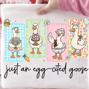 May include: White t-shirt featuring four cartoon geese in Easter-themed settings. Each goose is in a different frame with pastel backgrounds. The text "just an egg-cited goose" is written in cursive at the bottom. The shirt is held by a person.