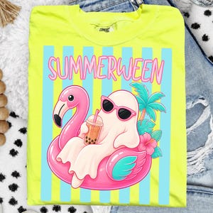 K&ouml;nnte beinhalten: Neongelbes T-Shirt mit einem Motiv eines Geistes mit Sonnenbrille, der auf einem rosa Flamingo-Schwimmring liegt und Bubble Tea trinkt. Das Shirt zeigt das Wort "SUMMERWEEN" in rosa Buchstaben &uuml;ber blauen und wei&szlig;en Streifen.