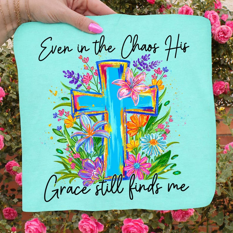 May include: A light blue square fabric with the text "Even in the Chaos His Grace still finds me." A large, colorful cross is the central design, surrounded by vibrant flowers in pink, orange, purple, and blue.