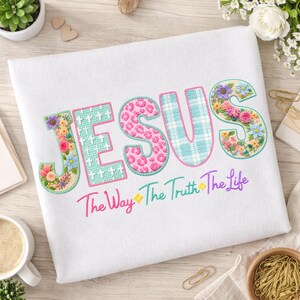 Puede incluir: Tela blanca con la palabra "JESUS" bordada en varios patrones y colores. Las letras est&aacute;n decoradas con dise&ntilde;os florales y de animales. Debajo, el texto "The Way The Truth The Life" est&aacute; bordado en degradado arco&iacute;ris.