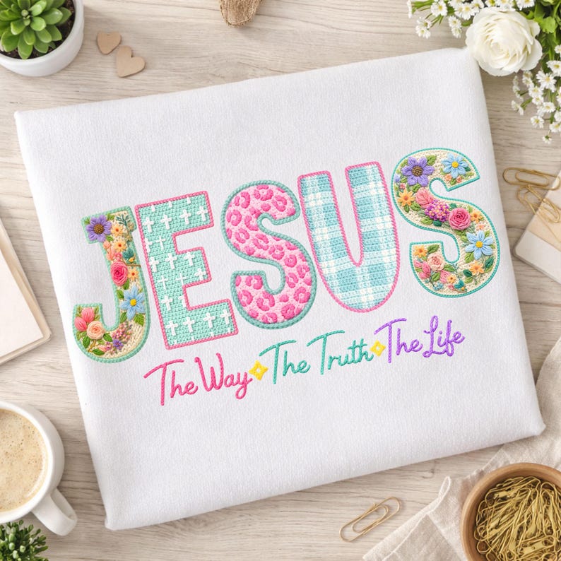 Puede incluir: Tela blanca con la palabra "JESUS" bordada en varios patrones y colores. Las letras est&aacute;n decoradas con dise&ntilde;os florales y de animales. Debajo, el texto "The Way The Truth The Life" est&aacute; bordado en degradado arco&iacute;ris.