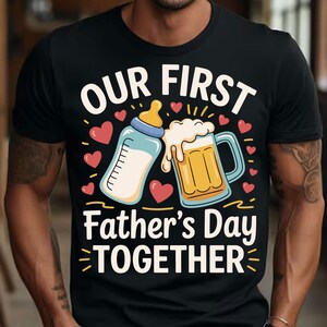 May include: Black t-shirt with a graphic design of a baby bottle and a beer mug. The text "Our First Father's Day Together" is printed on the shirt.