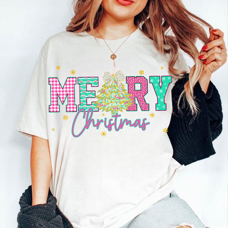 Puede incluir: Camiseta color crema con las palabras "MERRY Christmas" en un dise&ntilde;o colorido. Las letras "ME" son rosas y a cuadros, "R" es rosa con estampado de leopardo y "Y" es turquesa con copos de nieve. Un &aacute;rbol de Navidad y un lazo est&aacute;n en el centro.