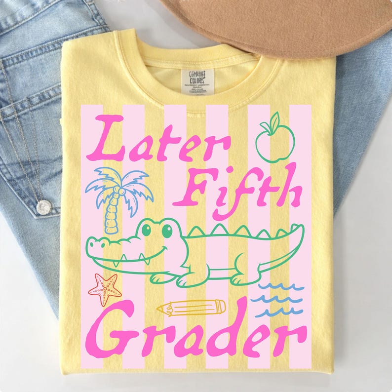 May include: Yellow t-shirt with a pink and white striped design. The shirt features the text "Later Fifth Grader" with a cartoon alligator, palm tree, apple, pencil, starfish, and waves graphic.