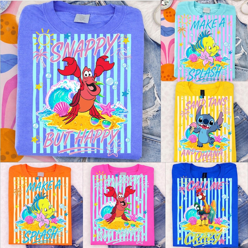 May include: A collection of colorful graphic t-shirts featuring cartoon characters and beach-themed designs. The shirts display phrases like "Snappy But Happy" and "Make a Splash" with vibrant illustrations of sea creatures and tropical elements.