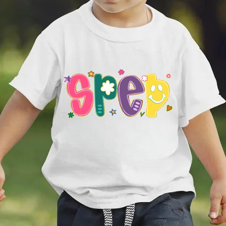May include: White t-shirt with the word "SPEEP" in colorful, playful letters. The letters are in pink, green, purple, and yellow, with decorative stars, flowers, and a smiley face. The shirt is for children.