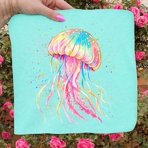 May include: A colorful jellyfish design on a light blue background. The jellyfish is painted with vibrant hues of pink, yellow, blue, and orange, with long, flowing tentacles. The design is on a square fabric, possibly a towel or pillow.